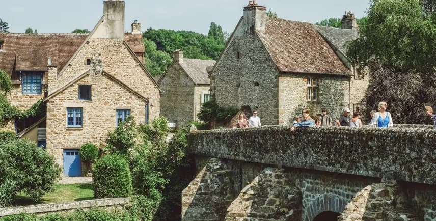Stone village buildings and bridge with people, historic European-style scene